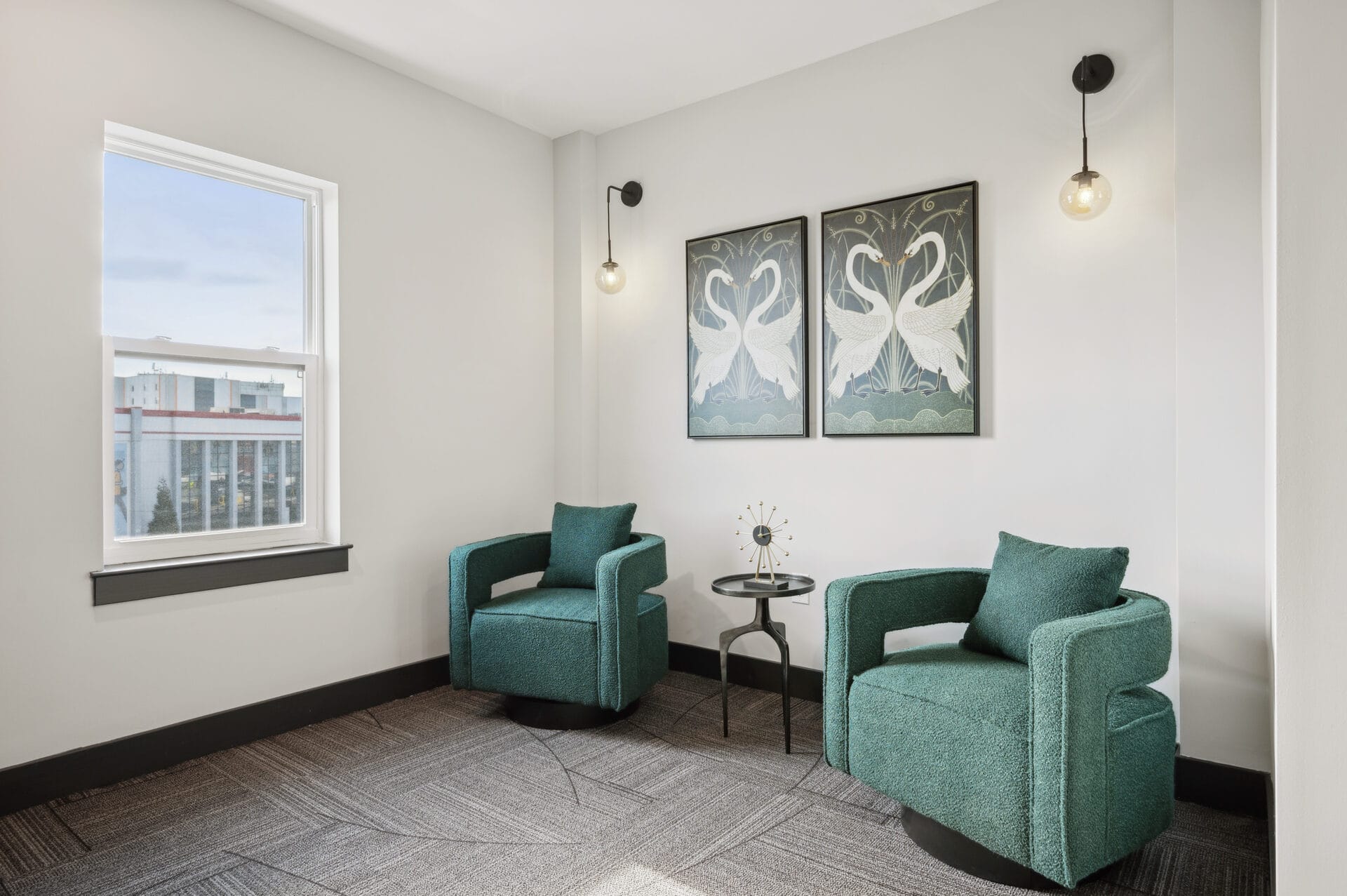 Resident seating nook at The Lane with teal boucle swivel chairs and framed crane art prints